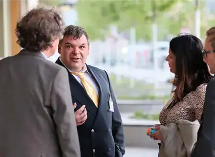 Ein Mann im Anzug spricht mit einigen Menschen.